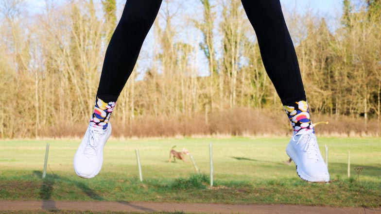 A person jumping in the air in their Walk Your Socks Off socks and white trainers