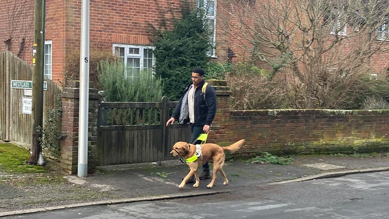 Devante and his guide dog, Mack, walk along the pavement together.