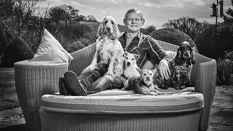 Marin Clunes sitting on a lounger with his dogs