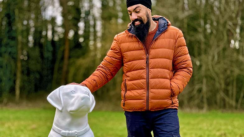 Artist MrASingh standing outside on the grass beside a blank guide dog sculpture