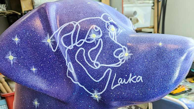 Close up of a decorated guide dog sculpture head painted purple with a star constellation pattern