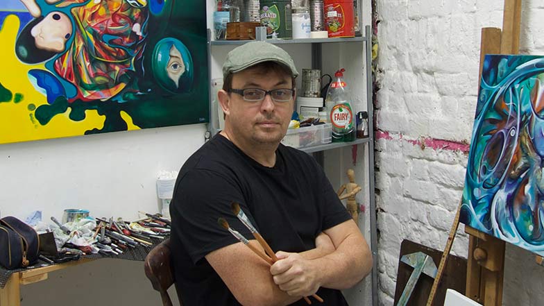 Artist Kevin Gavaghan sitting in his art studio looking to camera