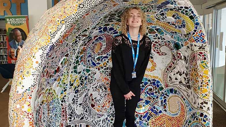 Artist Lauren Mullarkey standing under a large mosaic dome that she decorated.