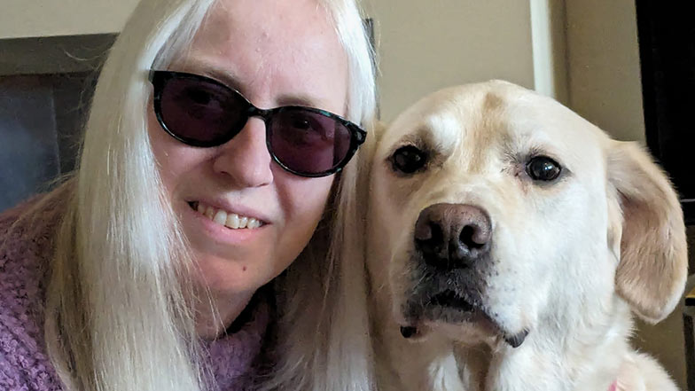 Close up of artist Sian Healey and her yellow Labrador guide dog Uri looking to camera