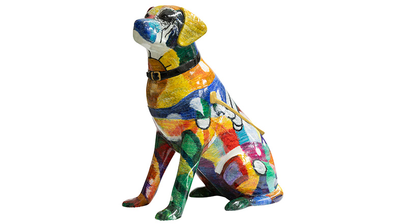 Painted guide dog sculpture with a black collar covered in with bright multicoloured swirls and patchwork like a knitted wool pattern.