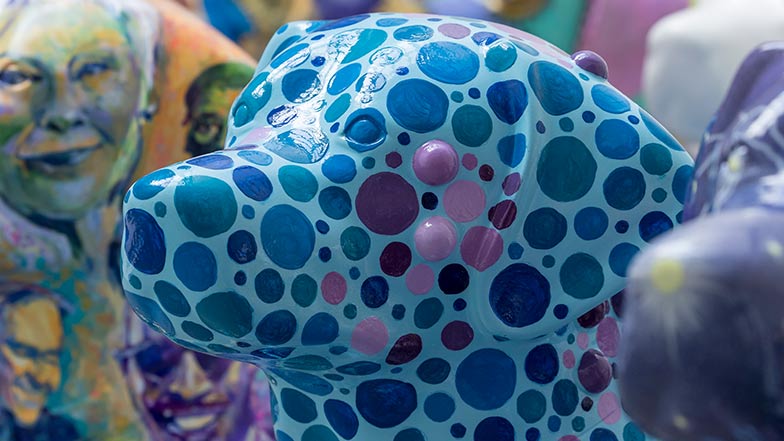 Close-up of the head of the Dot to Dog sculpture which is painted blue and covered in purple and blue dots