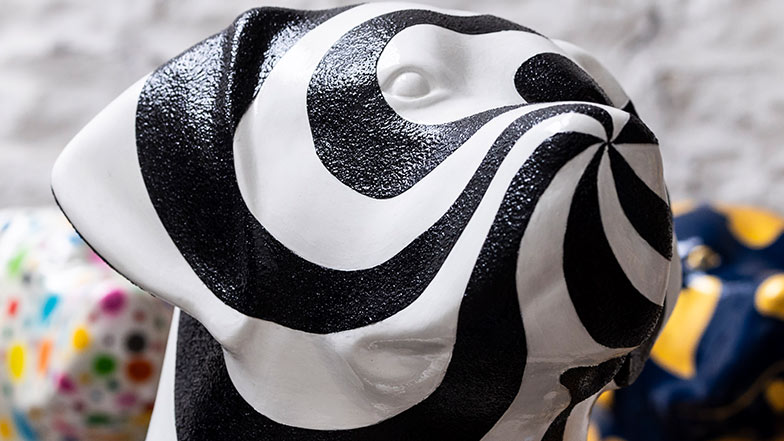 Close up of the sculpture's head which is painted in black and white swirls. The black paint is textured.