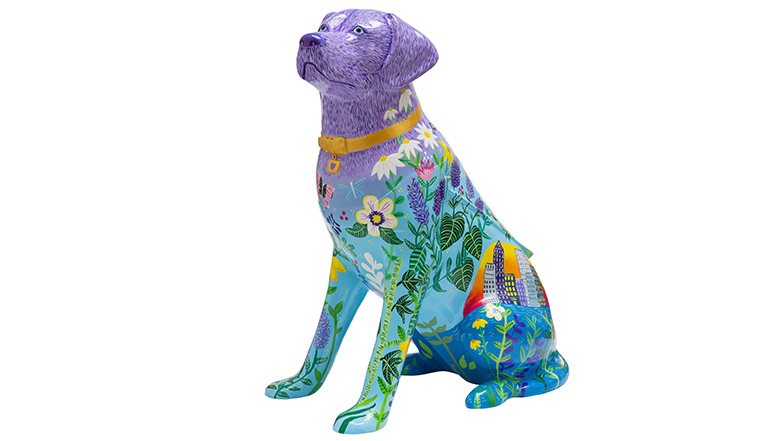 A  guide dog  sculpture wearing a gold collar with a purple head fading to a blue coloured body. The body is covered in colourful flora and fauna and features Canary Wharf cityscape illustrations.