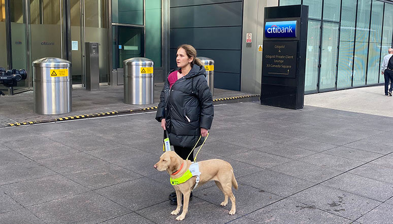 Guide dog owner Lorraine and guide dog Theia walk past the Citi office at Canary Wharf