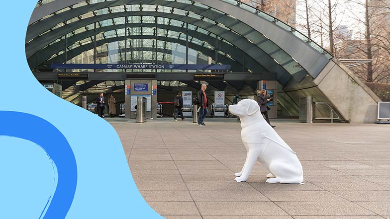 Blank white guide dog sculpture sat in front of the entrance to Canary Wharf tube station.