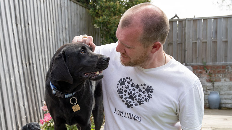 Guide dog owner and his guide dog a black Labrador looking at each other fondly.