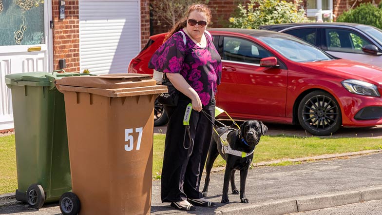 Sage guiding owner Leonie around dustbins which are blocking the pavement. Sage guiding owner Leonie around dustbins which are blocking the pavement.
