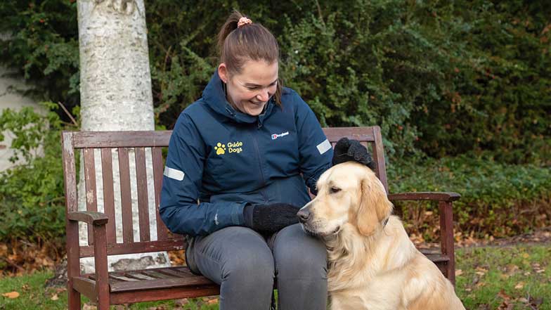 Sprouts trainer sits on a bench with Sprout beside her