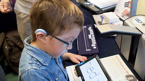 A boy using a screen magnifier on his tablet at a Guide Dogs event