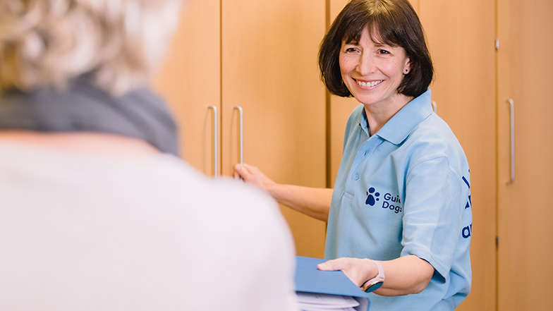 Guide Dogs staff member giving a folder to a service user