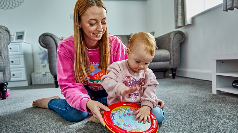 Eliza sitting on her mum's lap while banging a toy drum