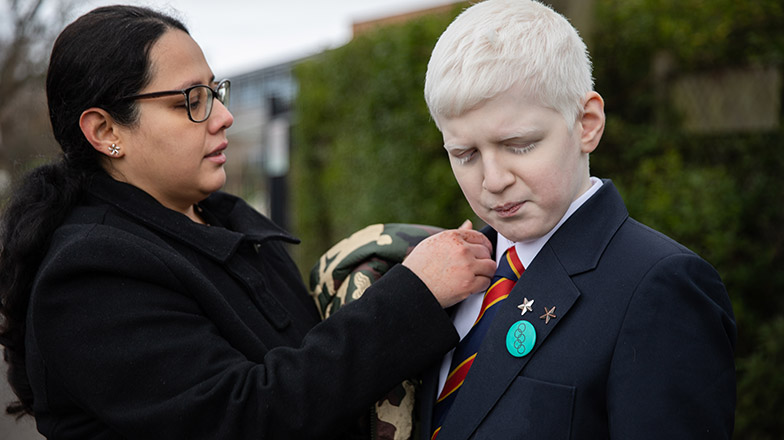 A picture of a mum tidying her son's school blazer before he goes into school