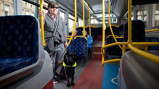 A young person on the bus with their guide dog