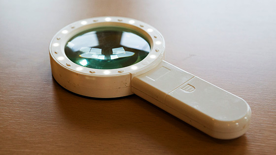 A white, illuminated hand held magnifier on a table