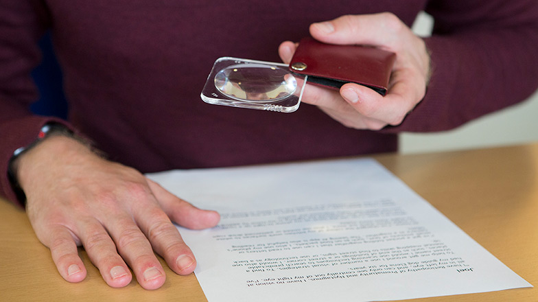 A man reading a letter with a non-illuminated pocket magnifier