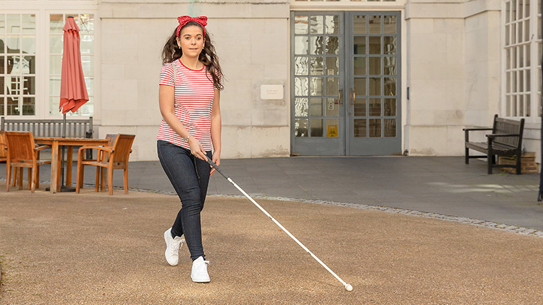 A women using her cane to navigate outside