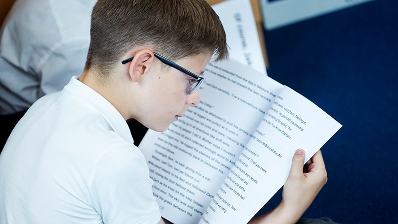 Image of a boy reading a large-print book from Guide Dogs 'CustomEyes Books service