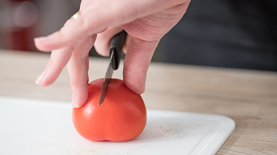 Person chopping tomato using the bridge technique
