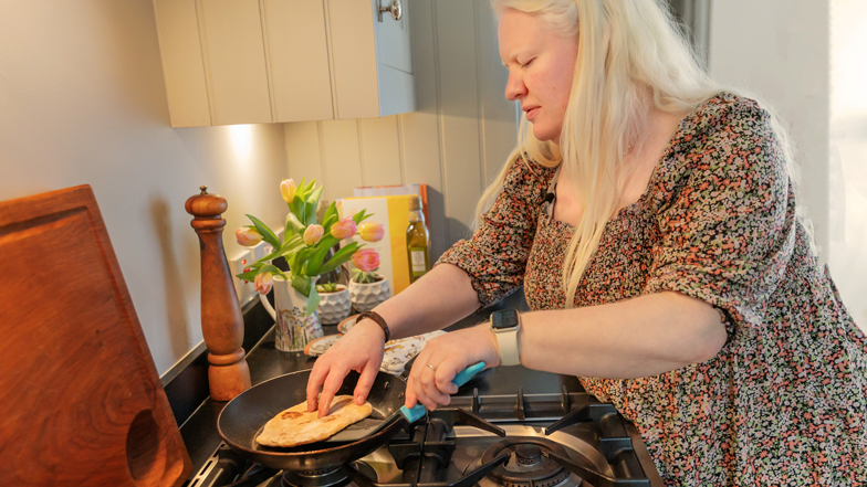 A woman with sight loss cooking on the hob