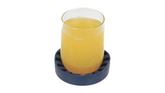 A glass of orange juice sitting in a blue dycem cup holder