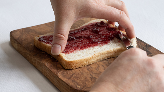 Someone using the tunnel technique to spread jam onto a piece of bread