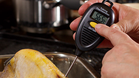 Someone using a talking thermometer to read the temperature of a roast chicken