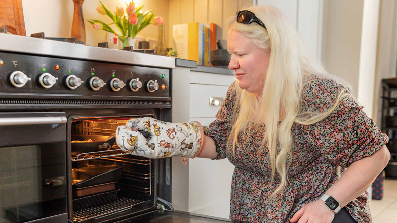 A woman with sight loss putting a frying pan in the oven