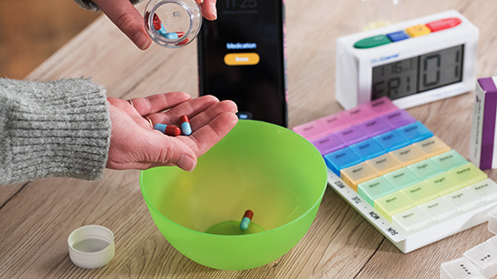 A person counting out pills over a bright green bowl