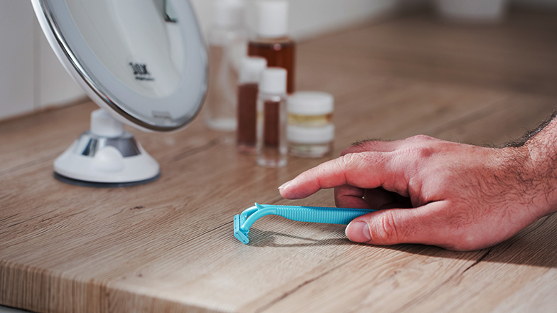 Hand picking up a disposable razor