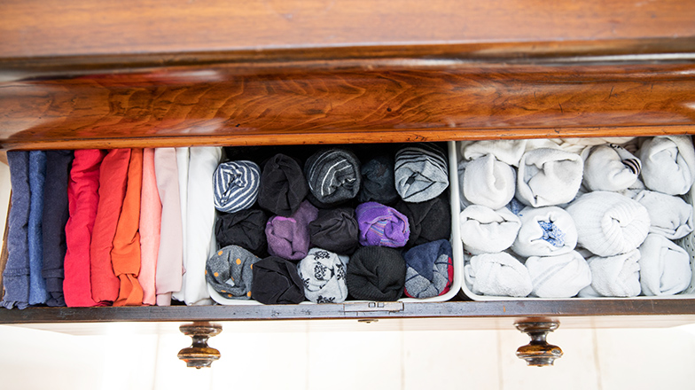 An organised drawer with a section for white socks, a section for black socks and a section for coloured t-shirts