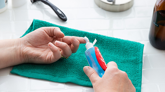 Toothpaste being squeezed onto a finger with a washcloth underneath