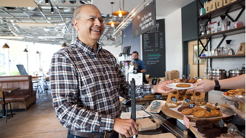 Man smiles whilst in a cafe using his cane