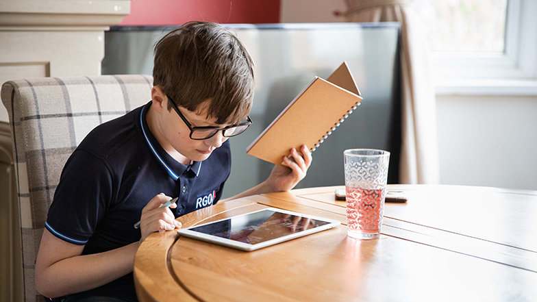 Boy using iPad and holding a notebook