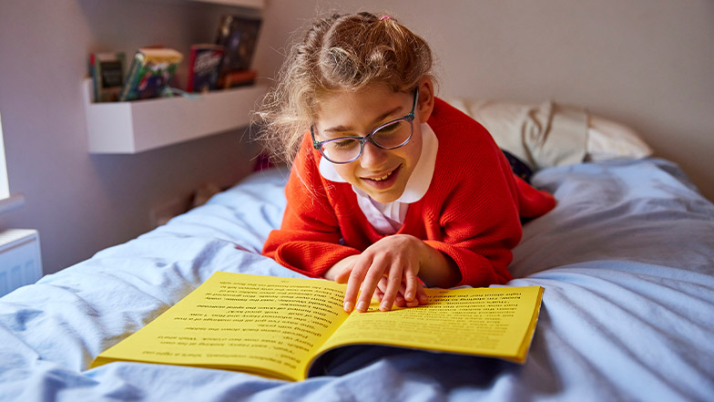 A girl in her school uniform laying on the bed reading