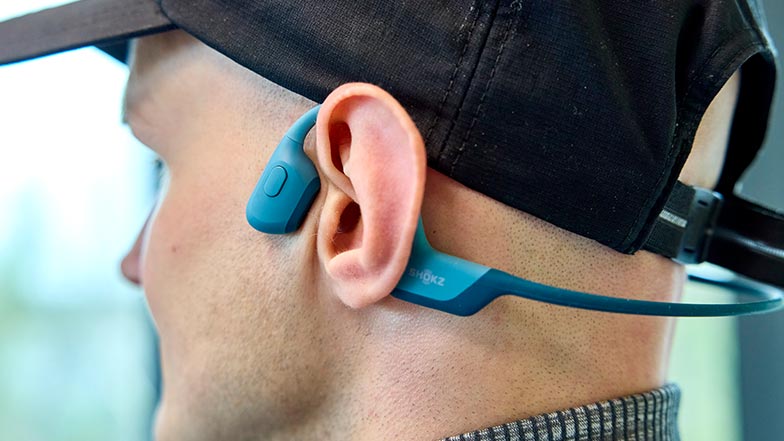 A close-up of a man wearing Shokz bone conducting headphones.