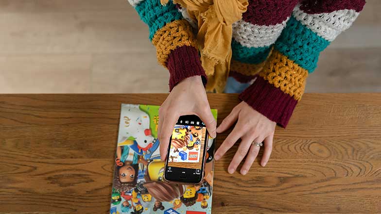 A lady with vision impairment using the Seeing AI app on her phone to read a magazine.