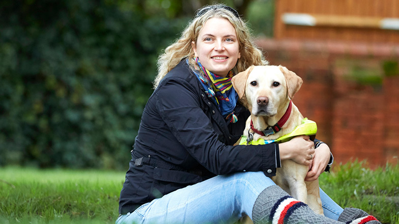 Volunteer and guide dog owner Anica smiles with her guide dog