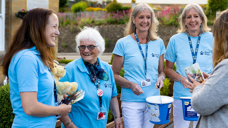 A group of volunteer fundraisers smile as they talk to a member of public