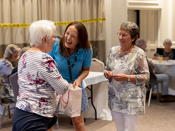 Sue (on the right, wearing a grey top) is at a Guide Dogs event