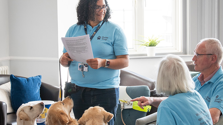 Volunteer speaks to people whilst three dog looks up at her