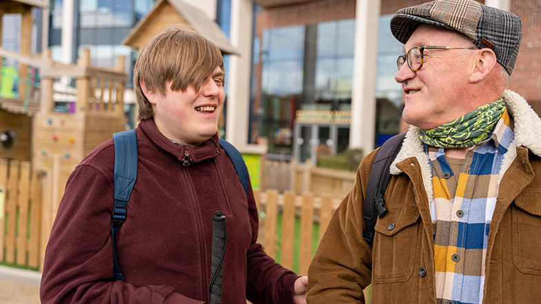 A young man with a cane is being guided by a male sighted guide volunteer 